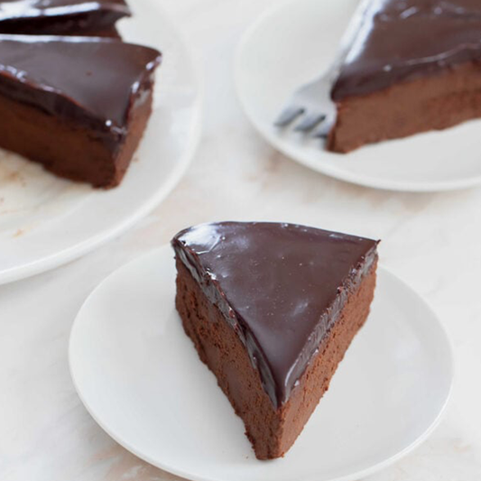 Slices of chocolate cake on white plates with a light background